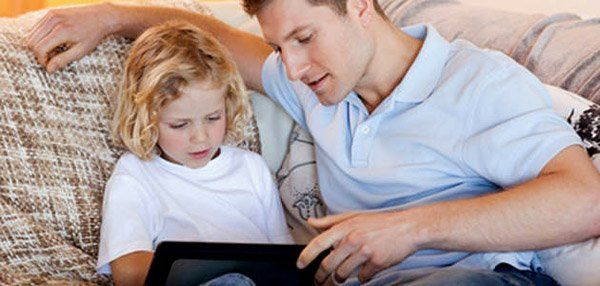 Father and son using tablet on the sofa