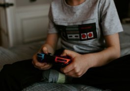 kid sitting on gray bed while playing